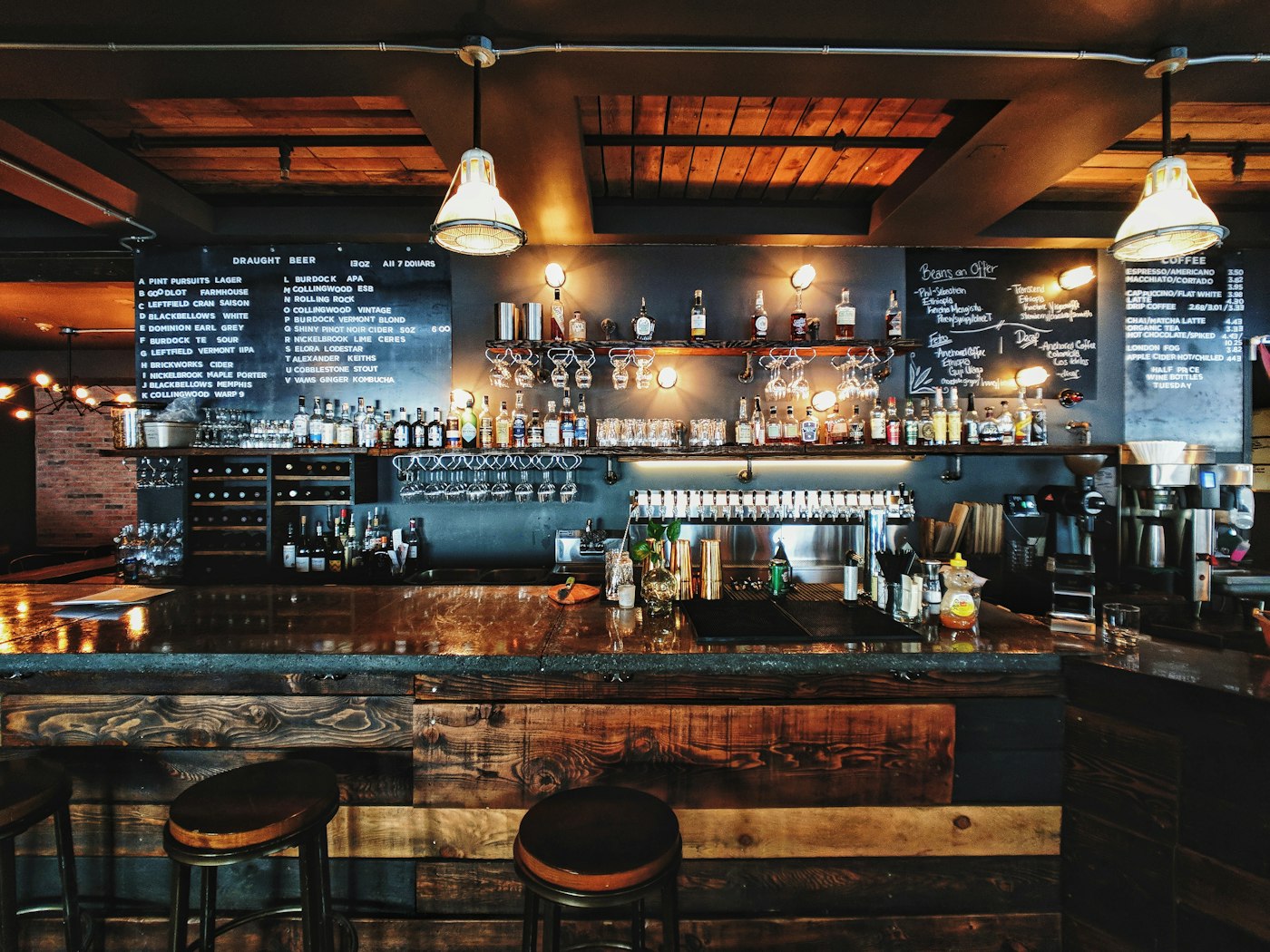 Balcão de bar com banquetas e prateleira de bebidas
