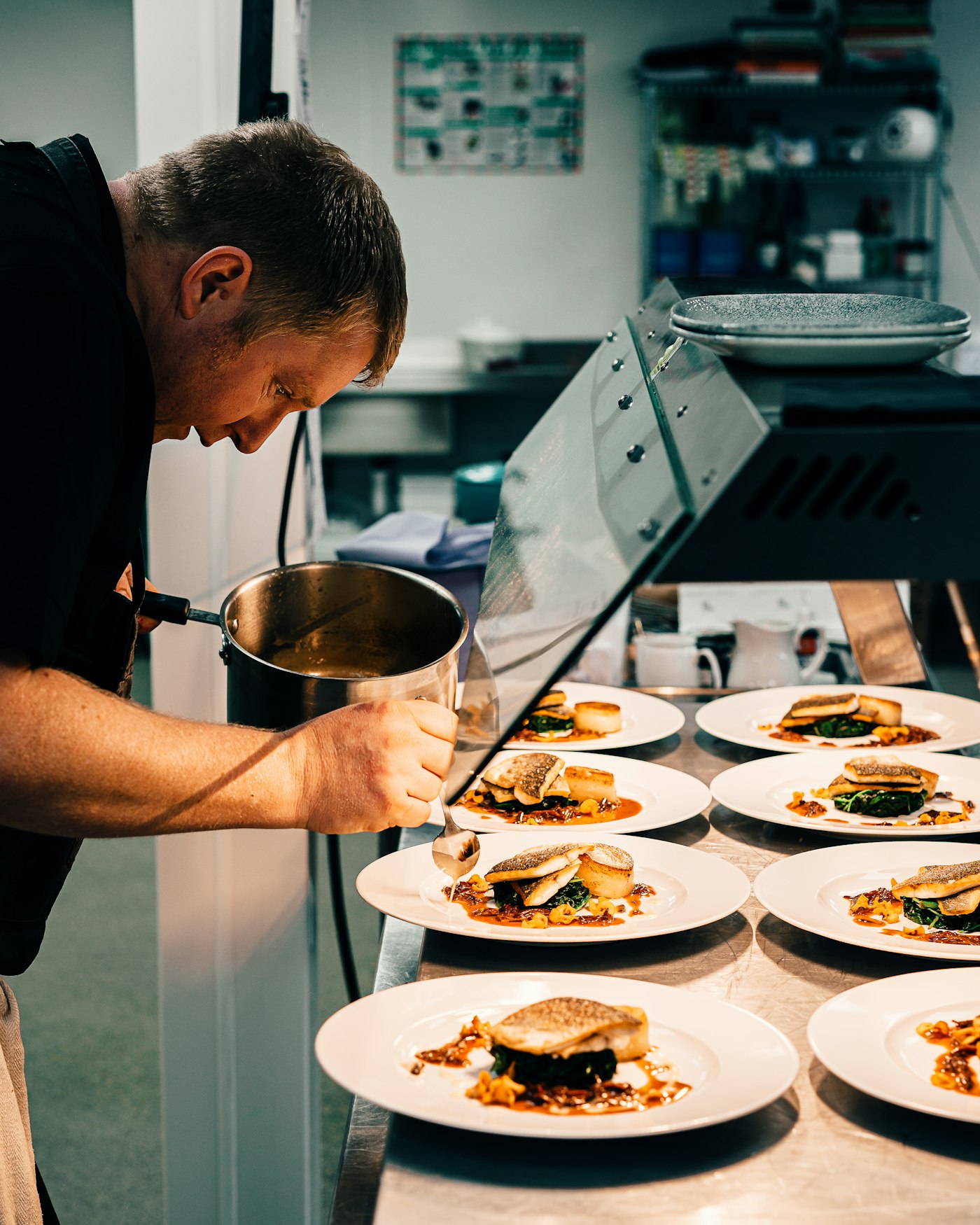 Chef finalizando pratos na expedição com tablet ao lado